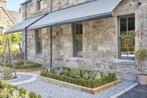 a stone house with awning and plants in front of it at The Grandtully Hotel in Grandtully +10 photos