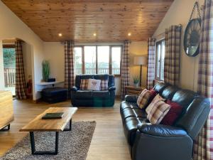 a living room with a leather couch and a coffee table at Kingfisher Lodge with Hot Tub in Cupar