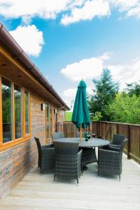 a patio with a table with a green umbrella at Kingfisher Lodge with Hot Tub in Cupar