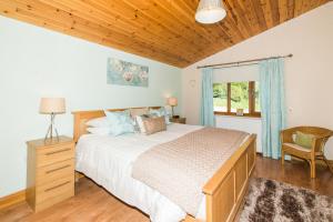 a bedroom with a large bed and a wooden ceiling at Kingfisher Lodge with Hot Tub in Cupar