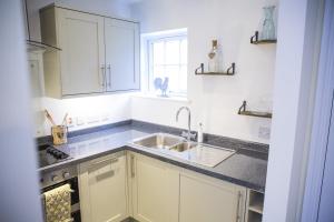 - une cuisine avec des placards blancs et un évier dans l'établissement 1-Bed Apartment - FREE Parking - Town Centre, à Stratford-upon-Avon