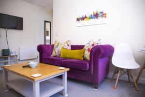 uma sala de estar com um sofá roxo e uma mesa em 1-Bed Apartment - FREE Parking - Town Centre em Stratford-upon-Avon
