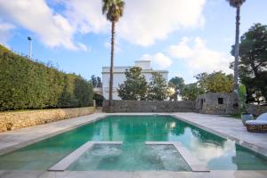 una piscina en un patio con palmeras en SA Suites, en Trepuzzi