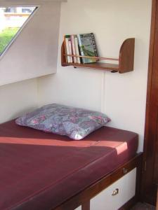 Cama con almohada y ventana en una habitación en Pénichette Lady Sarah, en Hennebont