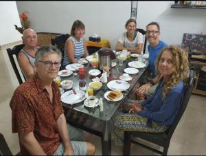 a group of people sitting around a table eating food at Snehatheeram Homestay in Alleppey