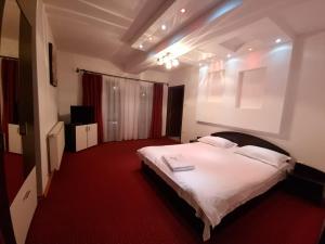 - une chambre avec un grand lit blanc et un tapis rouge dans l'établissement PENSIUNEA LUXURY, à Vama