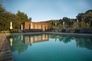 Ein Pool mit Liegestühlen und Sonnenschirmen neben einer Hütte in der Unterkunft Hotel Mas del Sol in Vall-llobrega