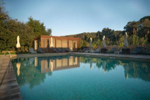 a pool with chairs and umbrellas next to a cabin at Hotel Mas del Sol in Vall-Llobrega