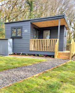 a tiny house with a porch and a deck at HiveAway - Hot Tub - Carmarthenshire - Pembrokeshire in Mydrim