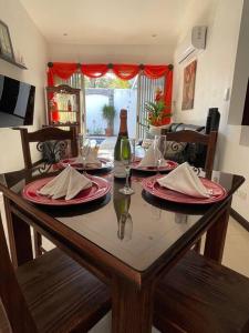 tavolo da pranzo con piatti rossi e bicchieri da vino di Casa Encanto Luz del Mar, Con Piscina Privada a Herradura