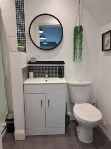 a white bathroom with a toilet and a mirror at Suffolk View Apartment in Tuddenham