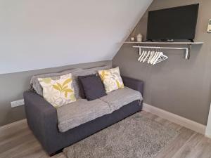 a couch with pillows and a television in a room at Suffolk View Apartment in Tuddenham