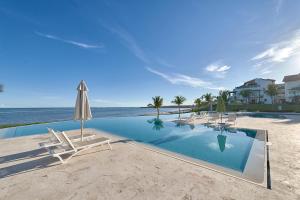 una piscina en la playa con sillas y sombrilla en Punta Palmera Beach Front 3b apartment Cap Cana en Punta Cana