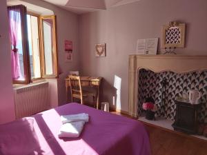 a bedroom with a purple bed and a fireplace at B&B Le Rupicapra in Roubion