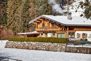 a log cabin in the snow with a stone wall at Hauser Kathrin und Martin in Fieberbrunn