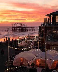 a beach with tents and a pier at sunset at Cosy Courtyard Apartment in Kemptown in Brighton & Hove