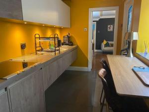 une cuisine avec des murs jaunes, une table et un comptoir dans l'établissement Cosy Courtyard Apartment in Kemptown, à Brighton et Hove
