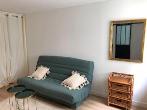 un sofá verde en la sala de estar con espejo en BLUE Studio cosy et calme proche du centre avec TV et Wifi, en La Rochelle