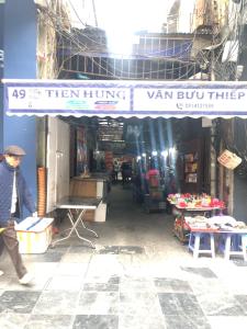 a man walking under a sign in a market at TrangTien Hostel in Hanoi
