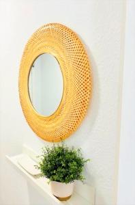 un espejo de mimbre colgado en una pared con una planta en Precioso y amplio estudio en Puerto de La Cruz, en Puerto de la Cruz