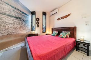 a bedroom with a red bed and a large painting on the wall at Ti case a moin - Joli T2 en bord de mer in Saint-Pierre