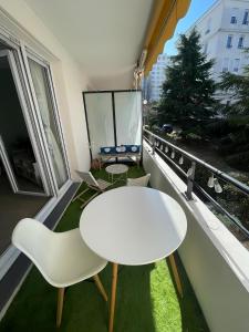 d'une table et d'une chaise blanches sur un balcon. dans l'établissement « Esprit cosy », terrasse, piscine, proche Lyon, à Tassin-la-Demi-Lune