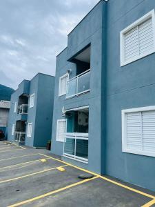 een blauw gebouw met witte ramen en een parkeerplaats bij Apartamento Com Churrasqueira Maranduba Ubatuba! in Ubatuba