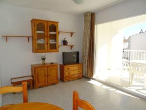 a living room with a tv and a wooden cabinet at AL203 céntrico, piscina y garaje AL203 in Alcossebre