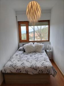 een slaapkamer met een bed met 2 kussens en een raam bij El Coqueto de Segovia in El Espinar