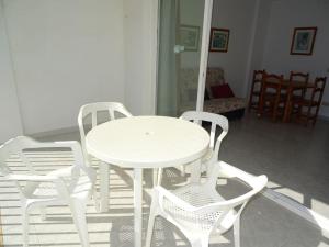 a white table and four white chairs in a room at AL203 céntrico, piscina y garaje AL203 in Alcossebre