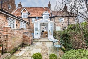a brick house with a white door and a patio at Quaint Cottage in the heart of North Yorkshire Village - Pet Friendly FREE in Stillington