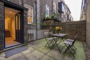 a patio with two chairs and a table with flowers on it at Goodge Apartments in London
