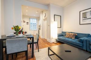 Goodge Apartments في لندن: غرفة معيشة مع أريكة زرقاء وطاولة