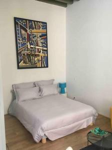 sypialnia z białym łóżkiem z obrazem na ścianie w obiekcie Studio Anna centre historique Bordeaux St Pierre w mieście Bordeaux