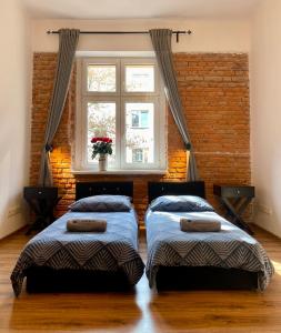 two beds in a room with a window at Topolove Rooms & Apartments in Krakow