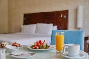 a table with a plate of fruit and a glass of orange juice at Fiesta Americana Condesa Cancun - All Inclusive in Cancún