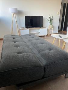 a large grey couch in a living room with a tv at Temporario La Plata2 in La Plata