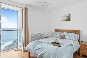 a bedroom with a bed with a view of the ocean at 14 At The Beach, Torcross in Beesands