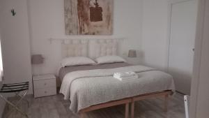 a white bedroom with a bed and a chair at Montevecchi13 in Imola