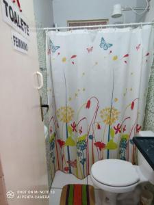 a bathroom with a toilet and a shower curtain with butterflies at Mandala Camping - Oferecemos um espaço para sua barraca in Alto Paraíso de Goiás