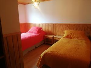 Habitación pequeña con 2 camas y lámpara en Hotel Cochamó en Cochamó