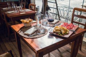 a wooden table with a plate of food and wine glasses at Agriturismo La Cerra in Tivoli