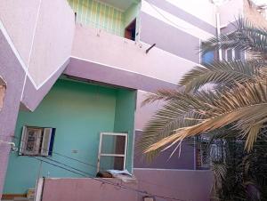 a purple and green building with a palm tree at Large and cheerful home with 2 floors in Fayoum Center