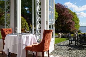 a table on a porch with a view of the water at Storrs Hall Hotel in Bowness-on-Windermere