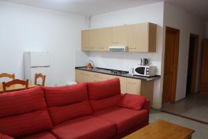 sala de estar con sofá rojo y cocina en Pozo Izquierdo Homelidays, en Pozo Izquierdo