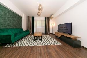 Il comprend un salon doté d'un canapé vert et d'une télévision à écran plat. dans l'établissement One Bedroom near Floreasca Park, à Bucarest