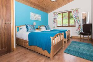 a blue bedroom with a bed and a chair at Skylark Lodge with Hot Tub in Cupar
