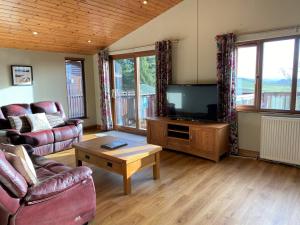 a living room with a couch and a television at Skylark Lodge with Hot Tub in Cupar