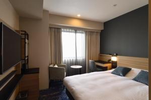 una camera d'albergo con un grande letto e una finestra di Hotel JAL City Miyazaki a Miyazaki
