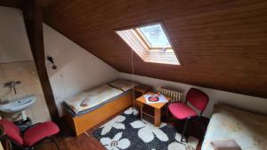 an attic room with a bed and a sink and two chairs at Penzion Olympia in Banská Bystrica